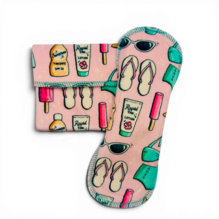 SoCo Studio PAD BEACH BABE (MINKY) reusable pad with pink background and beach-themed print: sunscreen, lotion, sunglasses, flip-flops, and popsicles.