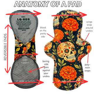 SoCo Studio reusable cloth menstrual pad featuring a sugar skull and marigold floral print with orange snap wings.